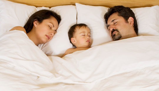 Bebé durmiendo en la cama de sus padres