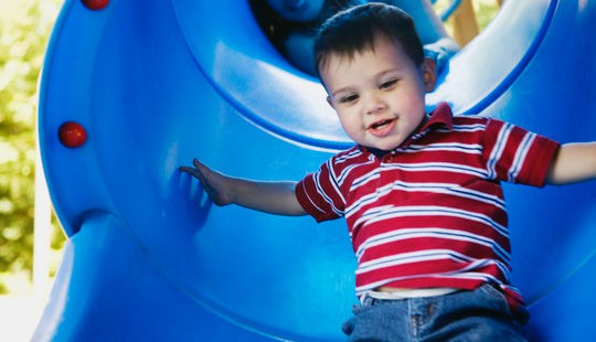 Niño tirándose por un tobogán del parque