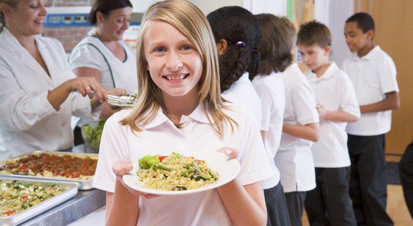 Grupo de escolares en la cola del comedor para recoger su menú diario