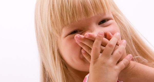 Niña tapándose la boca y riéndose