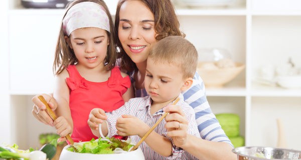 Madre preparando ensalada con sus hijos