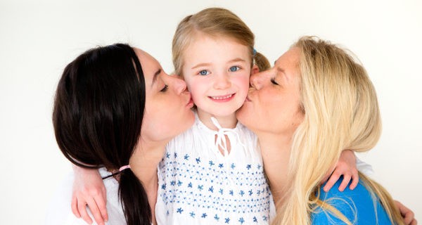 Madres dando un beso a su hija