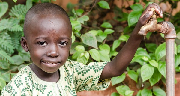 niño africano y grifo de agua