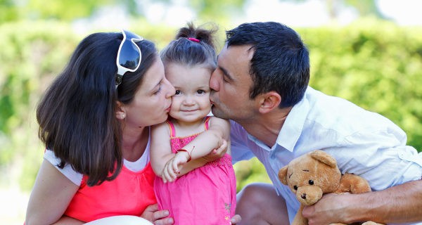 padres dando un beso a su hija