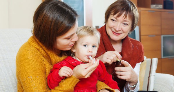 madre y abuela dando medicamento al niño
